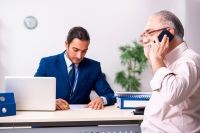 Foto: Pensionist telefoniert, Sachbearbeiter am Schreibtisch